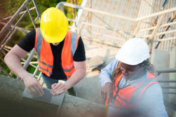 Male and female engineers working on construction site, They are inspecting the cement plaster work...