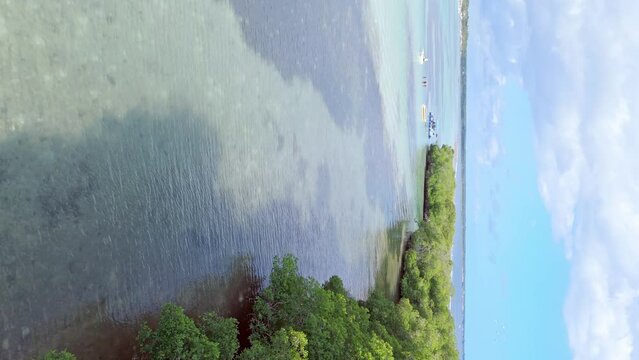 Drone flying over tropical sea along La Matica island, Playa Boca Chica beach in Dominican Republic. Aerial forward and vertical format