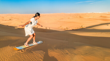 Dubai desert sand dunes, an Asian woman on Dubai desert safari, United Arab Emirates vacation,...