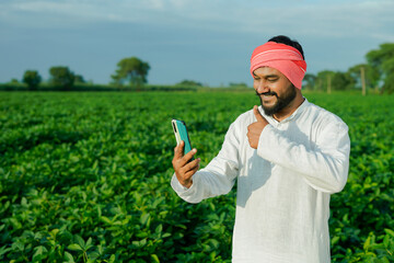 Indian farmer using smart phone at green farm field
