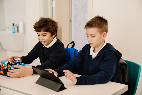 Two school boys working with constructor blocks and tablets at stem class