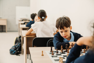 Group of school kids learning to play chess in classroom