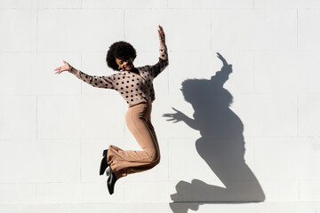 Carefree young happy woman jumping in the street. - Powered by Adobe