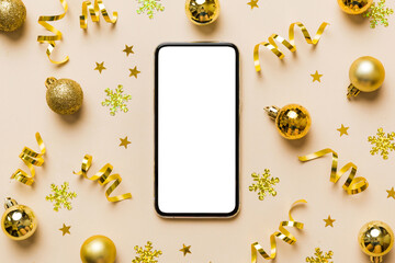 Christmas online shopping from home phone with blank white display top view. smart mobile with copy space on colored background with Christmas decorations balls,. Winter holidays sales background