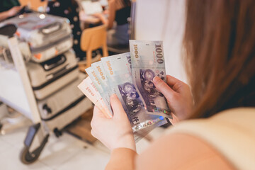 Close-up view of young woman holding  New Taiwan Dollar in shopping mall