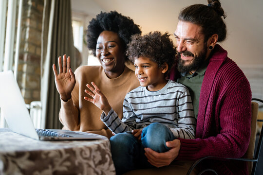 Happy multiethnic diverse family gathering around notebook and having fun during a video call