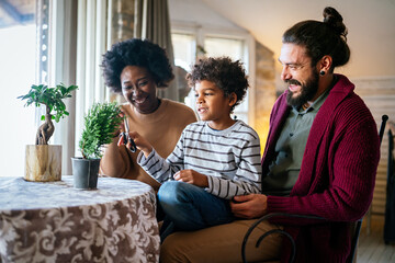 Happy diverse couple, parent with her children taking care of plants indoors. Family love concept.