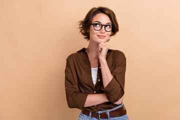 Photo of pretty dreamy girl dressed brown shirt eyewear arm chin looking empty space isolated beige...