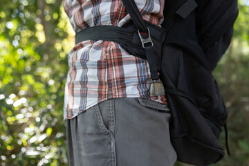A person who wear a backpack with bear bell at the green forest in Autumn