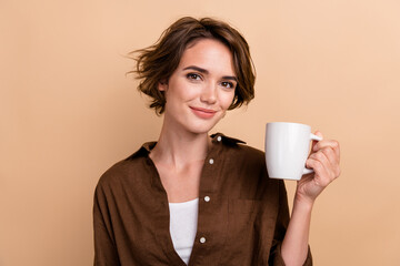 Photo of pretty cheerful lady wear brown shirt enjoying drinking coffee isolated beige color...
