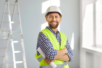 Portrait of smiling builder or architect in hardhat inside new house. Happy bearded man in hard hat...