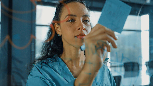 Young hispanic employee writing on colorful sticky notes. Smart businesswoman sharing marketing idea, brainstorming strategy, business plan. Project manager drawing mind map. Closeup. Manipulator.