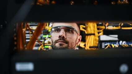 Young man is working with internet equipment and wires in server room