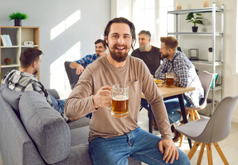 Group of happy friends drinking beer at home together. Cheerful men partying, drinking beer drinks,...
