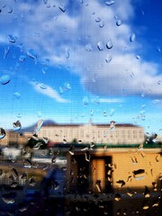 raindrops on the glass with blue sky and buildings in the background