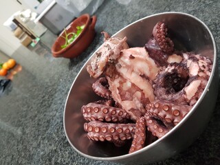 Fresh raw octopus in a metal bowl on the kitchen table.