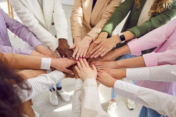 Team of young, diverse, mixed race, multiethnic business women all together holding their hands...