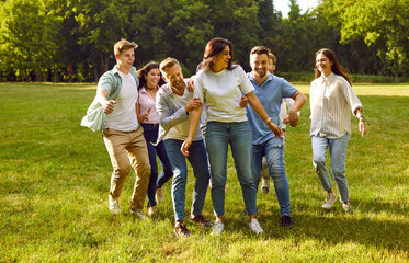 Group of young people hugging in the park. Happy, cheerful, joyful friends relaxing, having fun and hugging in a sunny, fresh, green park on a nice summer weekend