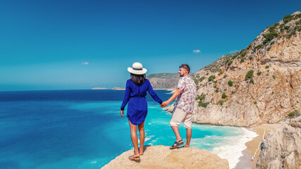 Obraz premium couple on vacation Turkey Kaputas Beach Kas Turkey, white orange beach from cliffs by the ocean of Kas Turkey rivera during summer, men and woman standing on cliff looking ocean during summer vacation