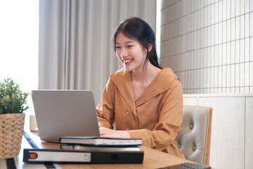 Young attractive Asian woman smiling thinking planning writing in notebook, tablet and laptop...