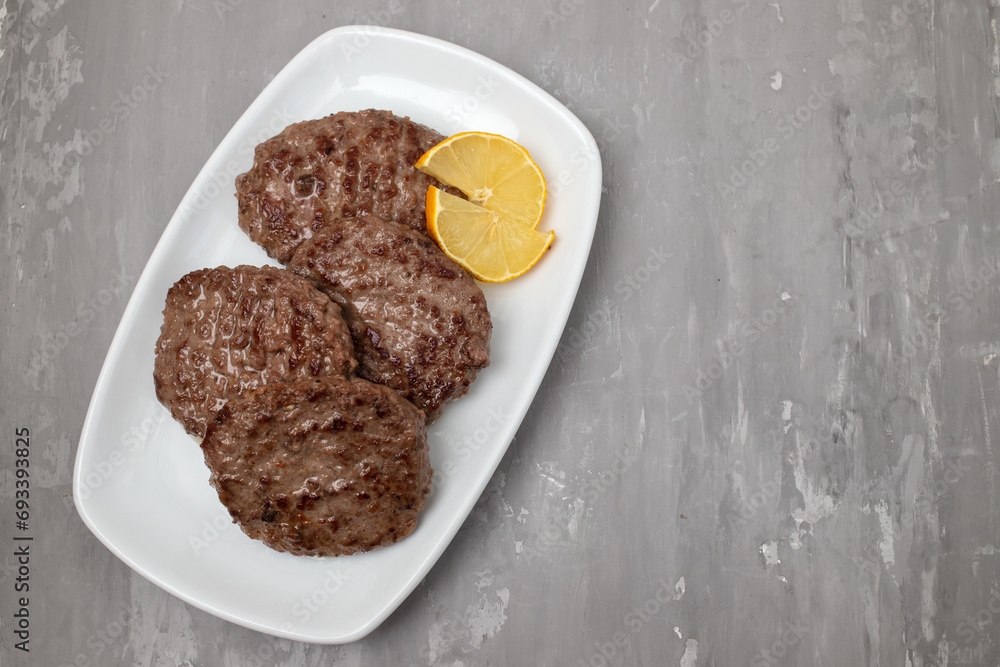 Sticker fried cutlet for burger with lemon. In a white plate