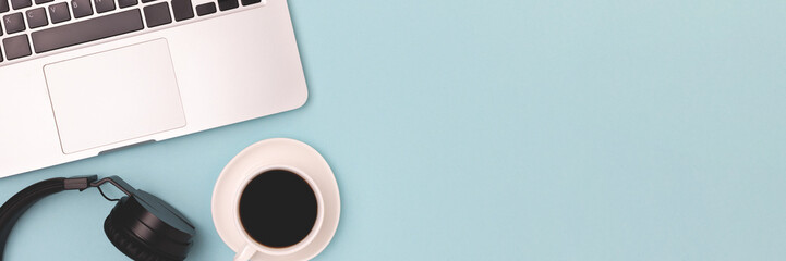 Banner with headphones, black coffee and laptop on a blue background. Online work concept with copy...