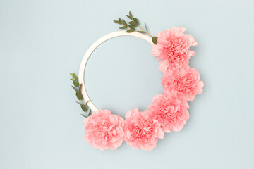 Wreath made of pink carnation flowers and green eucalyptus branches on a blue background. Cute...