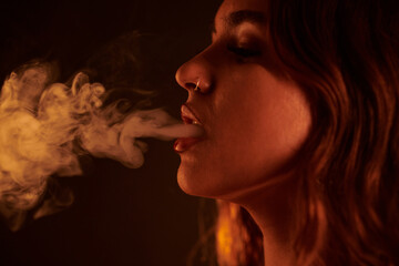 Young woman with piercing exhaling smoke of hookah - obrazy, fototapety, plakaty