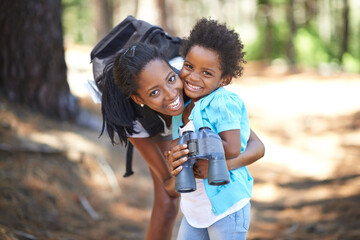 Portrait, binocular or black family hiking in forest to relax, hug or bond on holiday vacation together in nature. Child, happy or mom in woods or park to travel on fun outdoor adventure with smile - obrazy, fototapety, plakaty