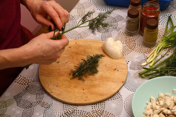 Crop anonymous female chef in uniform cutting fresh green parsley with knife on cutting board in...
