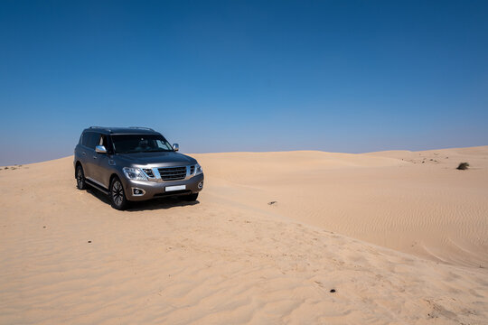 SUV four wheel drive vehicle car Al Qudra empty quarter seamless desert sahara in Dubai UAE middle east with wind paths and sand hills gray cloudy sky