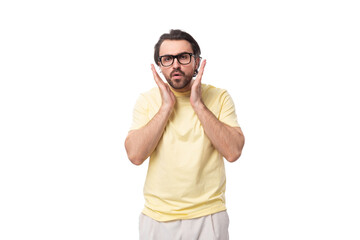 young handsome european brunette guy with a beard and mustache in glasses stands in surprise on a white background with copy space