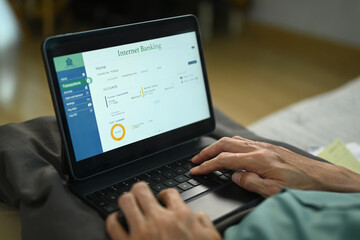 Man using digital tablet at home for reviewing bank account. Technology and finances concept.