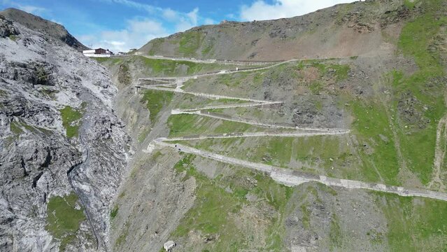 Flight over serpentine road towards summit of Stelvio Pass and mountain alps panorama in Italy