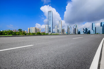 Asphalt highway road and urban skyline with modern buildings under blue sky