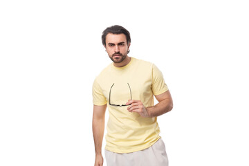 fashionable young successful European guy with stubble and mustache dressed in a light yellow T-shirt put on glasses