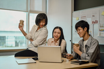Businesspeople using laptop computer and discussing project planning at co working space.