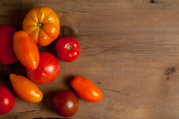 Assort of different shape and color tomatoes on wooden background..