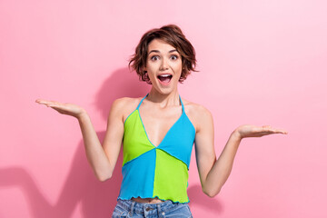 Portrait of amazed funny young girl hold two open palms demonstrating novelty product wear crop top...