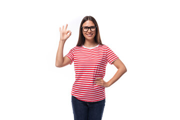 Obraz na płótnie Canvas young smiling energetic brunette woman with glasses dressed in a striped t-shirt on a white background with copy space