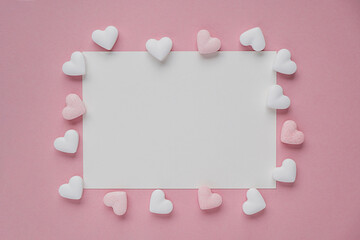 blank white mockup card with hearts for Valentine's Day on pink background. Flat lay, top view. Romantic love letter for Valentine's Day.