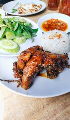 a plate of grilled duck breast served with chili sauce and vegetables such as cucumber and basil leaves