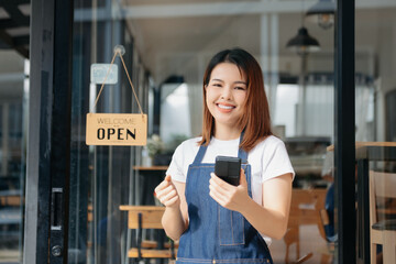 Young female hanging a welcome sign in front of a coffee shop. Beautiful waitress or hostess...