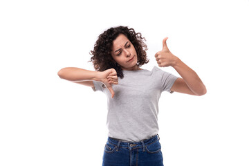 young active brunette curly woman dressed in a gray basic corporate color t-shirt actively gesturing with her hands on a white background with copy space