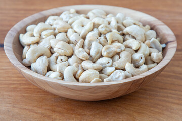 Cashews in a wooden bowl. Nuts are healthy food. Wooden background. Cashew kernel