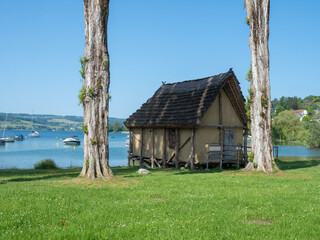 Lake Constance, Germany - May 29th 2023: Historic pile dwelling under old trees in front of the lake.