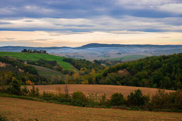 The picturesque authentic Italian landscape with villa, cypresses and plowed field in Tuscany,...