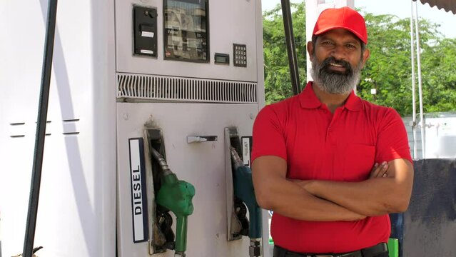 Petrol pump worker at petrol station - gas filling station  petrol vending machine  employment  petroleum service  blue collar job  Indian economy. A man working at a gas station - red uniform  pet...