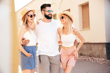 Group of young three stylish friends posing in the street. Fashion man and two cute female dressed...
