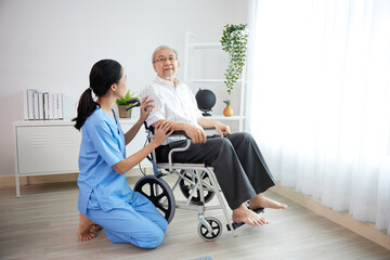 nurse or caregiver and elderly man sitting on wheelchair at home